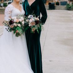 two women standing next to each other in front of a building with flowers on it