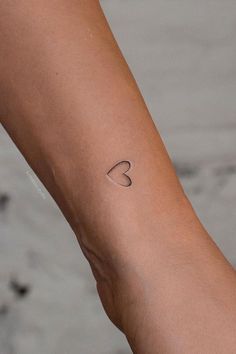 a woman's arm with a small heart tattoo on the left side of her arm