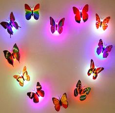 a group of colorful butterflies on a white wall with pink and blue lights in the shape of a heart