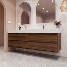 a bathroom with two sinks and mirrors on the wall next to a vase with flowers