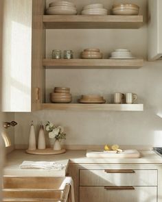 the shelves in this kitchen are filled with plates and bowls, cups and vases