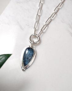 Stunning rose cut teal blue teardrop Kyanite gemstone set in sterling silver with a sterling silver bead design. The Kyanite pendant hangs from a sterling silver paperclip chain and clasp. D E T A I L S . . . . . . . .  Metal: Sterling Silver Gemstone: Kyanite Chain Length: 16", 17", 18" Pendant Dimensions: 30mm x 15mm Handmade jewelry with Love and Passion by Grace Lilly Designs. Handcrafted in the USA. Sapphire Teardrop Pendant Necklace In Sterling Silver, Sterling Silver Teardrop Necklace With Gemstone Accents, Sterling Silver Teardrop Necklace With Silver Clasp, Blue Teardrop Pendant Necklace In Sterling Silver, Blue Sterling Silver Teardrop Pendant Necklace, Silver Briolette Gemstone Drop Necklace, Silver Drop Necklace With Gemstone Accents, Silver Oval Apatite Jewelry, Silver Drop Necklace With Birthstone