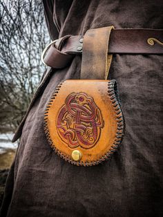 a person wearing a brown jacket with a leather belt around their waist and an intricate design on the side