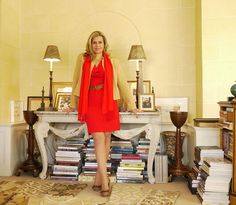 a woman in a red dress standing next to a table with many books on it