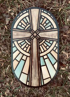 a stained glass window sitting on top of the grass in front of a wooden cross