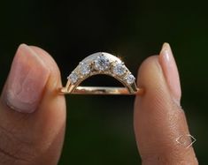 a woman's hand holding a gold ring with three diamonds on top and bottom