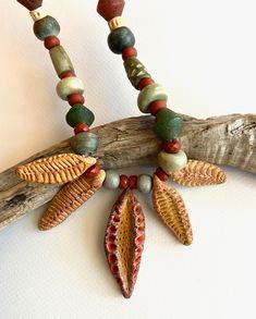 a necklace made with beads and leaves on a branch