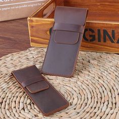 a brown leather case sitting on top of a wicker basket next to a wooden box