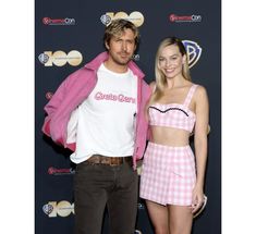 a man and woman standing next to each other in front of a red carpeted wall