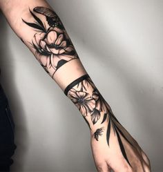 a person's arm with black ink flowers on it and an arrow in the middle