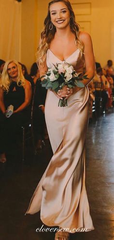 a woman is walking down the runway wearing a dress with flowers in her hair and holding a bouquet