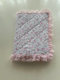 a pink and gray blanket with ruffles on it sitting on a white surface