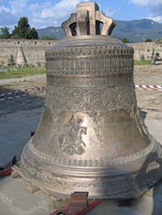 a large metal bell sitting on top of a sidewalk