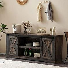 an entertainment center in a living room next to a wall with pictures and plants on it