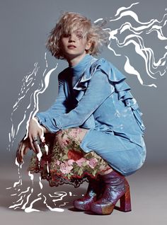 a woman sitting on top of a chair in front of a gray background with white swirls