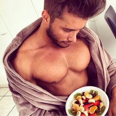 a shirtless man holding a bowl of food