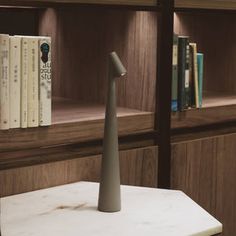 a book shelf with books and a white vase on the table in front of it