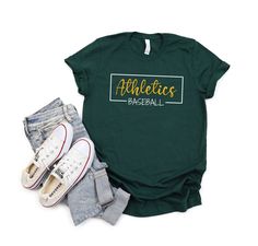 Do you love baseball? Do you love your Athletics? If so, then this is the shirt for you! This baseball shirt features Athletics graphics on the front and a comfortable fit. It's perfect for game day or any other occasion. Buy your A's baseball shirt today and show your support for your favorite team! UNISEX BELLA + CANVAS 3001 SHIRTS ABOUT UNISEX BELLA + CANVAS 3001 SHIRTS This jersey short-sleeve tee fits like a well-loved favorite. They are best-sellers and the soft cotton and quality print make users fall in love with it over and over again.  ⭐️ 100% preshrunk, combed and ringspun cotton (fiber content may vary for different colors) ⭐️ Light fabric (4.2 oz/yd² (142 g/m ⭐️ Tear away label ⭐️ Runs true to size ⭐️ Set-in sleeves ⭐️ Double-needle stitched bottom hem ⭐️ Twill taped shoulder Sporty Green Shirt With Letter Print, Green Varsity T-shirt With Letter Print, School Spirit Cotton Baseball Jersey With Letter Print, Sporty Cotton Baseball Jersey, Sporty Cotton Baseball Jersey With Letter Print, Sporty Pre-shrunk Shirt For Baseball Season, Relaxed Fit T-shirt For Baseball Season, Letter Print Shirt For College Baseball Season, Casual Green Baseball Jersey With Letter Print