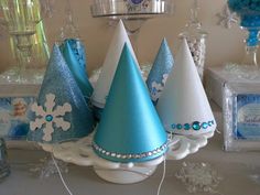 some blue and white party hats are on a table with snowflakes, candy