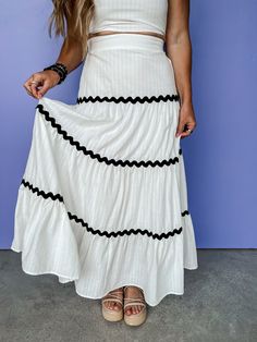 Get ready to breeze through summer in style with our Effortless Summer Tiered Maxi Skirt. This white skirt features trendy black ric rac trim accents, perfect for pairing with our Summertime Sense Top. Stay effortlessly chic and cool all season long! Lined Back elastic waistband Maxi length Fit: Relaxed; No stretch Waist: Small-25in Medium-27in Large-29in Length: Small-37in Medium-38in Large-39in Fabric: 100% Cotton Wash Instructions: Hand wash cold; Line dry Model: She is 5ft 2in and a size 4-6 Summer Black Cotton Maxi Skirt, Black Cotton Maxi Skirt For Summer, Chic Cotton Maxi Skirt For Vacation, White Lined Maxi Skirt For Vacation, Summer White Cotton Maxi Skirt, White Summer Cotton Maxi Skirt, White Cotton Summer Maxi Skirt, White Maxi Skirt For Spring Vacation, White Maxi Skirt For Vacation In Spring