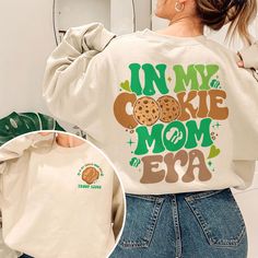 Elevate your Girl Scout style with our exclusive "In My Cookie Mom Era" sweatshirt. Crafted with the perfect blend of comfort and style, this shirt is a must-have for every proud Cookie Scout Mom. The eye-catching design celebrates the joys of being a Scout Mom, making it a perfect gift for Scout Leaders who truly embody the Camp Life spirit. Embrace the spirit of the Cookies Era with our uniquely designed Cookie Dealer shirts, add to your wardrobe today! 💥I. ABOUT PRODUCT - There are many ways to express your personality and wearing our products with eye-catching patterns and meaningful words is one of the ways. Comfortable, casual, and loose-fitting, our products will surely become one of your favorites. Made of cotton, safe and comfortable for anyone. - Using a unique water-based dyein Trendy Long Sleeve Tops With Funny Text, Trendy Tops With Funny Text For Mother's Day, Cute Long Sleeve Tops With Funny Text, Trendy Long Sleeve T-shirt For Mother's Day, Trendy Letter Print Sweatshirt For Mother's Day, Cute Slogan Tops For Mother's Day, Trendy Letter Print Sweatshirt As Gift, Trendy Cotton Sweatshirt For Mother's Day, Cute Mother's Day Slogan Tops