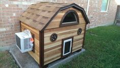 a dog house made out of wood with an air conditioner on the roof and windows