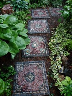 a garden path made out of stones and gravel with plants around the edges, surrounded by greenery