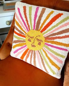 an orange chair with a colorful pillow on it's back and the face of a smiling sunburst