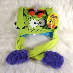 a green monster hat with purple pom poms