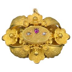 This is a rare and wonderful antique Victorian locket pendant with beautiful Ruby and Rose Cut Diamond adornments in stunning 14 Karat Gold. It is very rare to find antique jeweled Victorian Lockets. This beauty is set with a central flower motif design with a gorgeous natural fine red Ruby in the center and two wonderful Rose Cut Diamonds on either side. The jewels create the flowers and buds of the floral motif. The gold work in this locket is extraordinary. The piece is created with applied l Ornate Gold Locket Brooches, Victorian Locket Pendant Brooches, Victorian Brooches With Locket Pendant, Antique Jeweled Pendant Brooches, Antique Gold Brooches With Jewels, Antique Locket Brooch For Wedding, Flower Motif Design, Diamond Locket, Victorian Locket