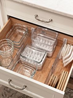 an open drawer in a kitchen filled with dishes and utensils on top of a counter