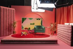 a red carpeted area with a green chair and pink walls in front of it