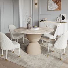 a dining room table with white chairs and a rug on the floor in front of it