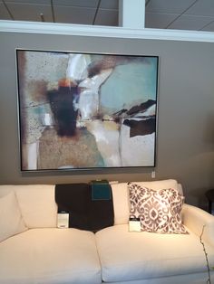 a white couch sitting in front of a painting on the wall