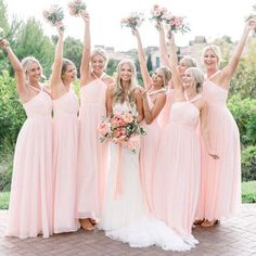 a group of bridesmaids in pink dresses holding bouquets and posing for the camera