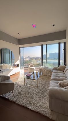 a living room filled with furniture and large windows overlooking the cityscape in the distance