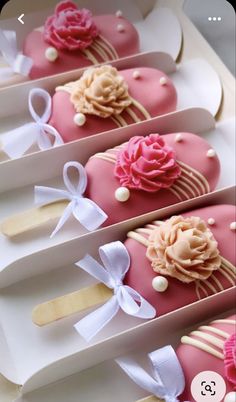 four decorated cookies in pink and white boxes with bows on the top one is shaped like an ice cream sundae