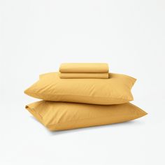 three pillows stacked on top of each other in front of a white background with yellow sheets