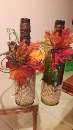 two vases filled with autumn leaves on top of a table