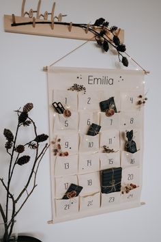 a white calendar hanging on a wall next to a vase with dried flowers in it