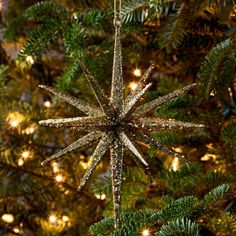 a star ornament hanging from the top of a christmas tree with lights on it