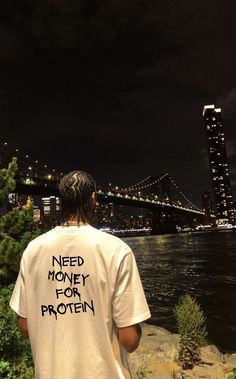 a man standing next to the water with a t - shirt that says need money for protein