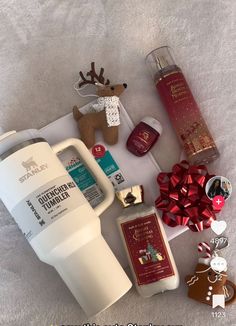 the contents of a christmas gift laid out on top of a white sheet with red bows