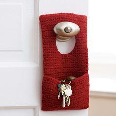 there is a red crocheted key holder attached to the doorknob with two keys in it