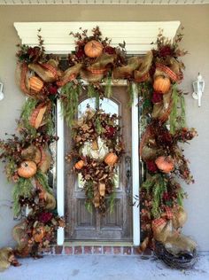 a front door decorated for fall with pumpkins and greenery on the wreathed wall