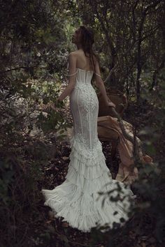 a woman standing in the woods wearing a white dress