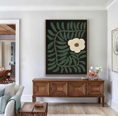 a living room filled with furniture and a painting on the wall over a coffee table