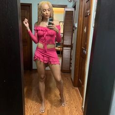 a woman taking a selfie in a mirror wearing a short pink skirt and top