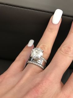 a woman's hand with white nails and a ring on her finger, in front of a car seat