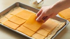 someone is cutting cheese into squares on a pan